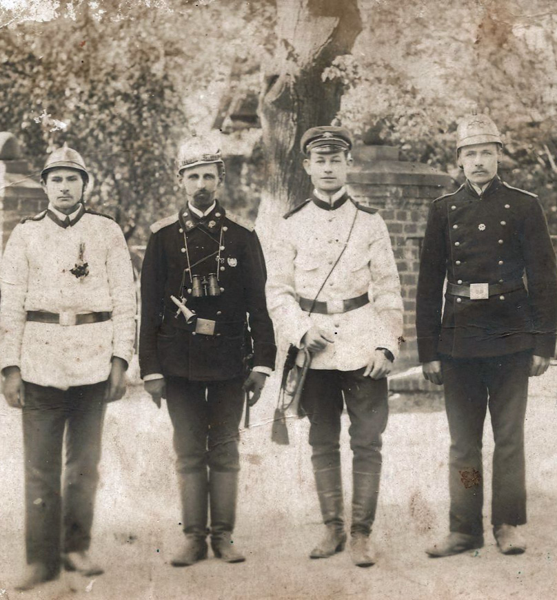 Czterech mężczyzn w strojach strażackich z początku dwudziestego wieku. Link do wyników wyszukiwania hasła OSP