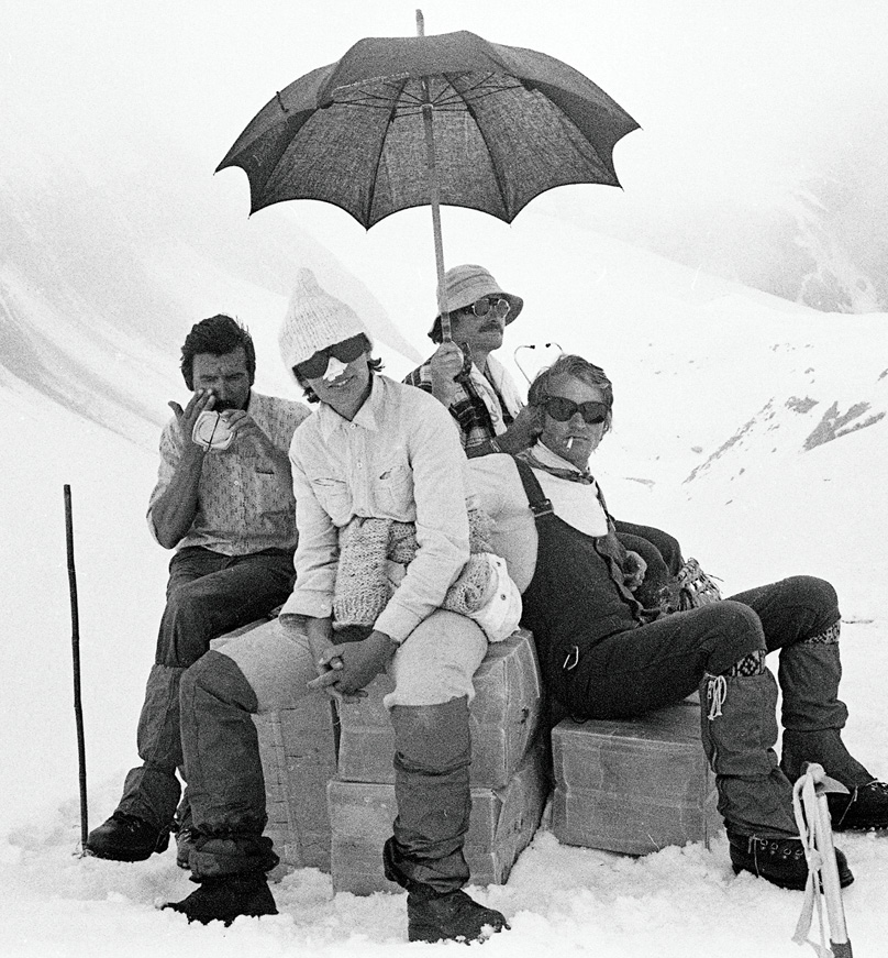 Czterech odpoczywających himalaistów. Jeden z nich trzyma w górze parasol. Link do podstrony z tym zdjęciem