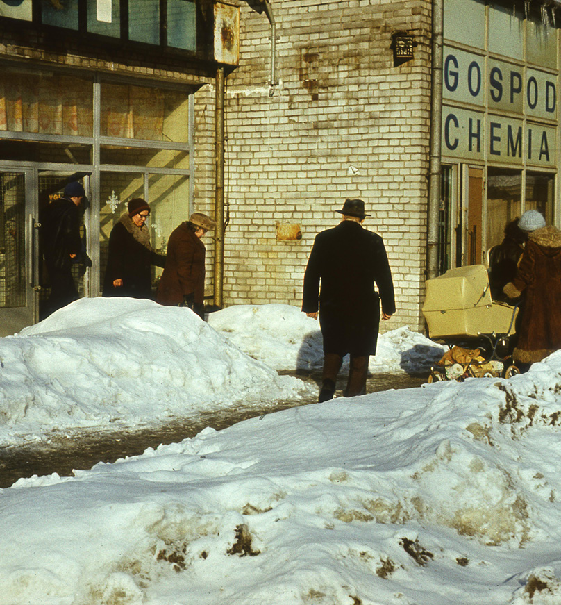 Ludzie przed pawilonami handlowymi, na pierwszym planie wysokie zaspy śniegu. Link do podstrony z tym zdjęciem