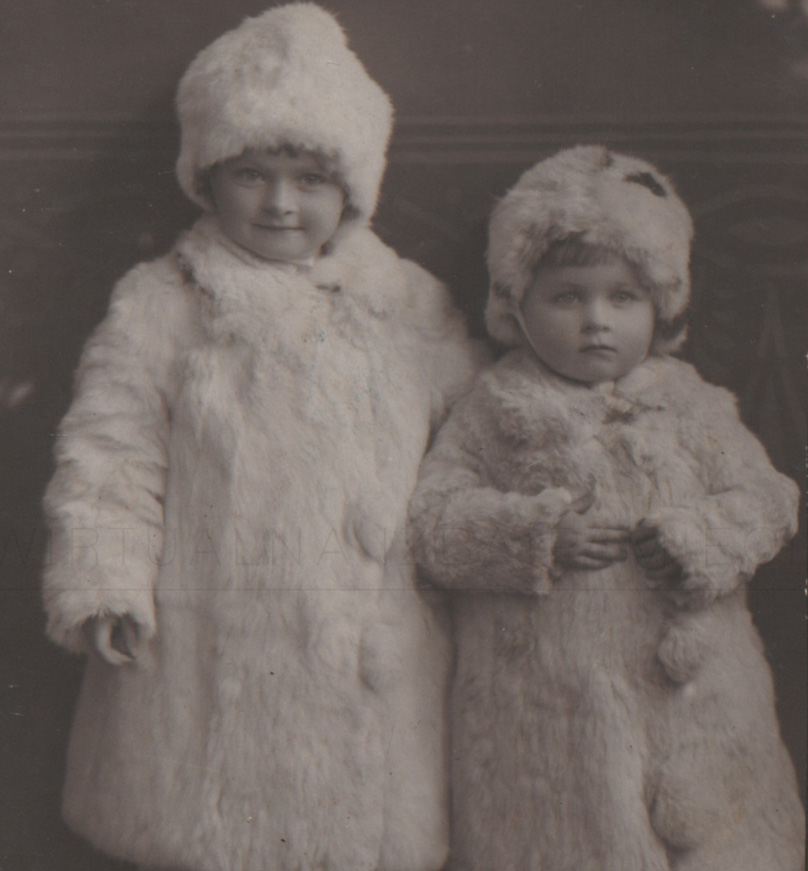 Dwoje dzieci w futrzanych czapkach i paltach. Link do podstrony z tym zdjęciem